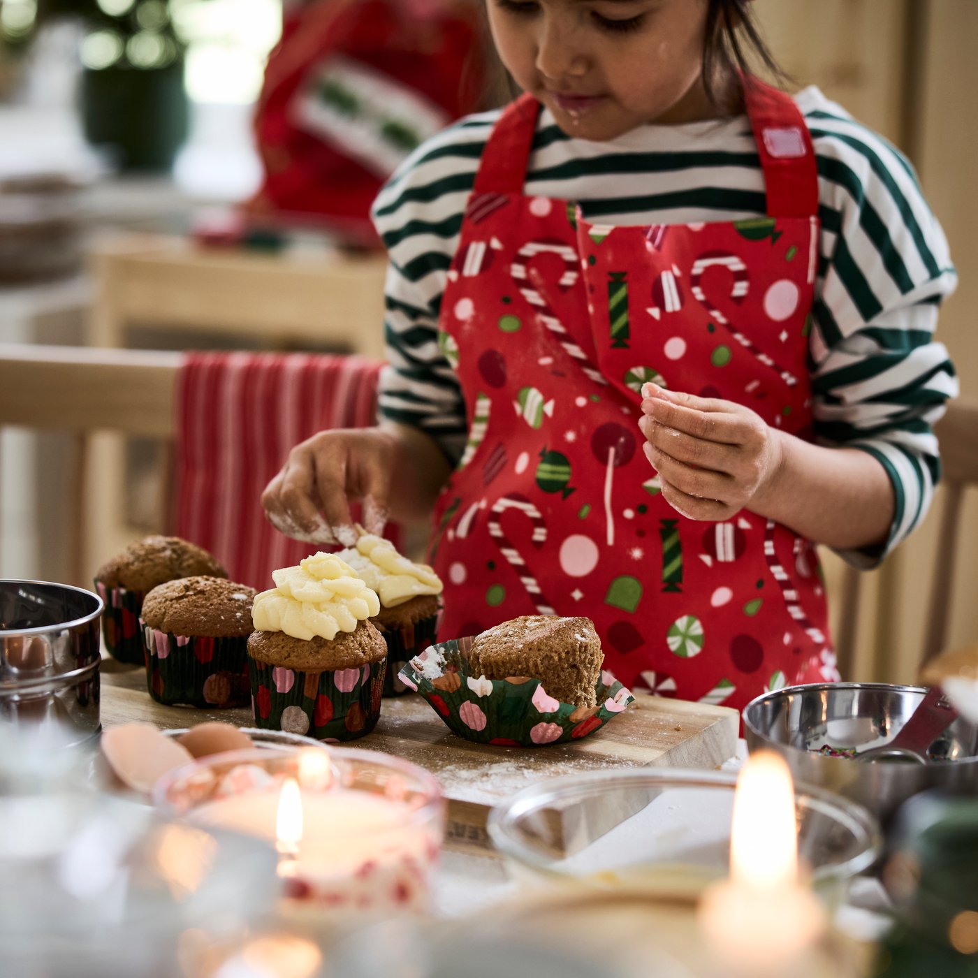 Una bambina con un grembiule VINTERFINT sta decorando dei cupcake.
