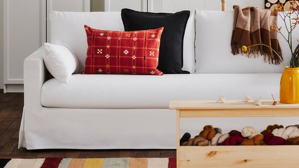 Vit soffa med avtagbart överdrag, dekorerad med röda kuddar i ett ombonat rum.