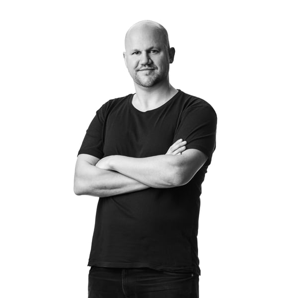 Portrait en noir et blanc du designer culinaire IKEA Daniel Yngvesson en t-shirt et jean foncé, dans un studio blanc.