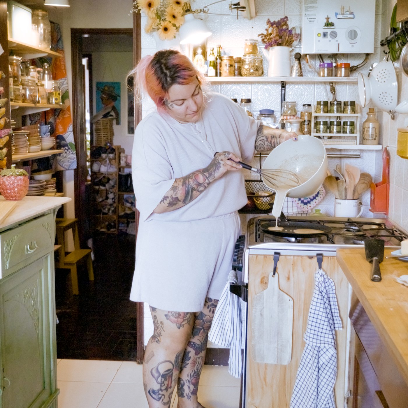 Una donna sorride mentre prepara i pancake in una padella HEMLAGAD sul fornello.