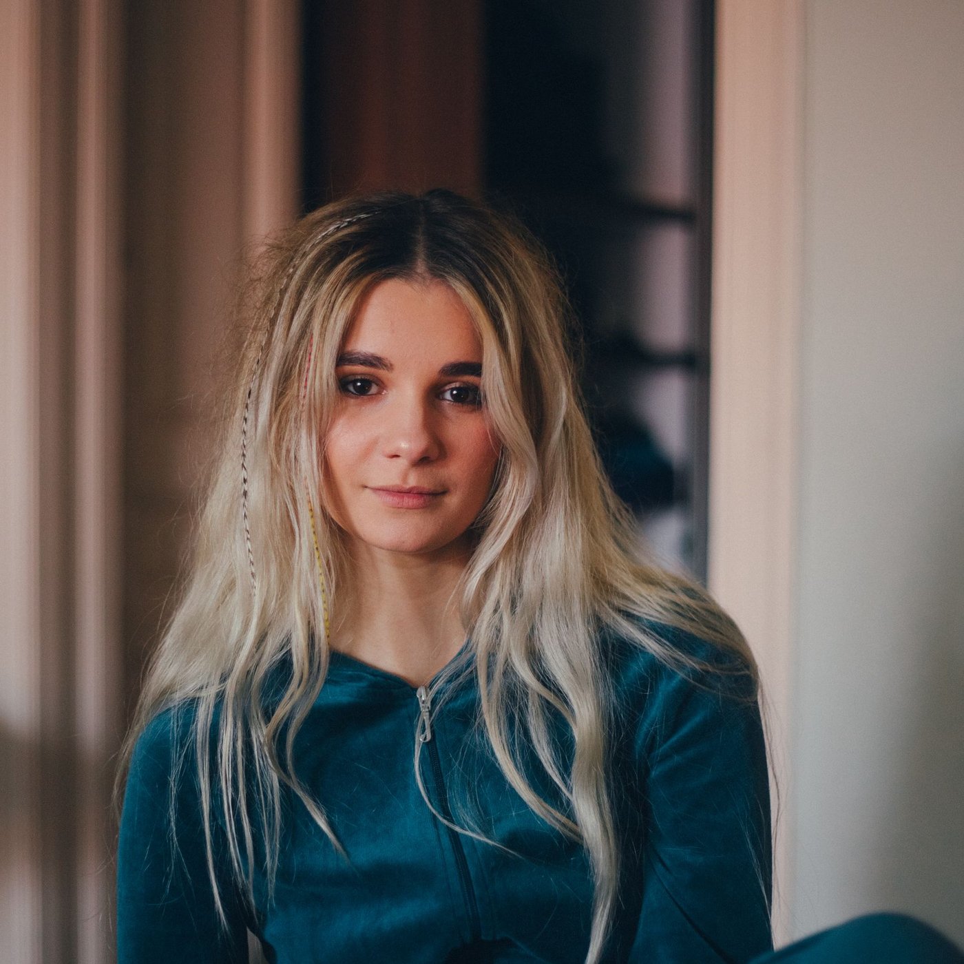 Yana at home wearing a green hoodie, she has some tiny braids in her hair.