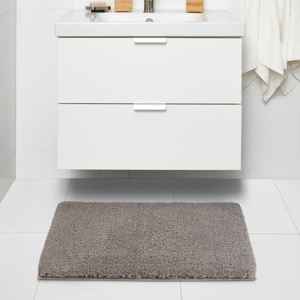 A beige ALMTJÄRN bath mat