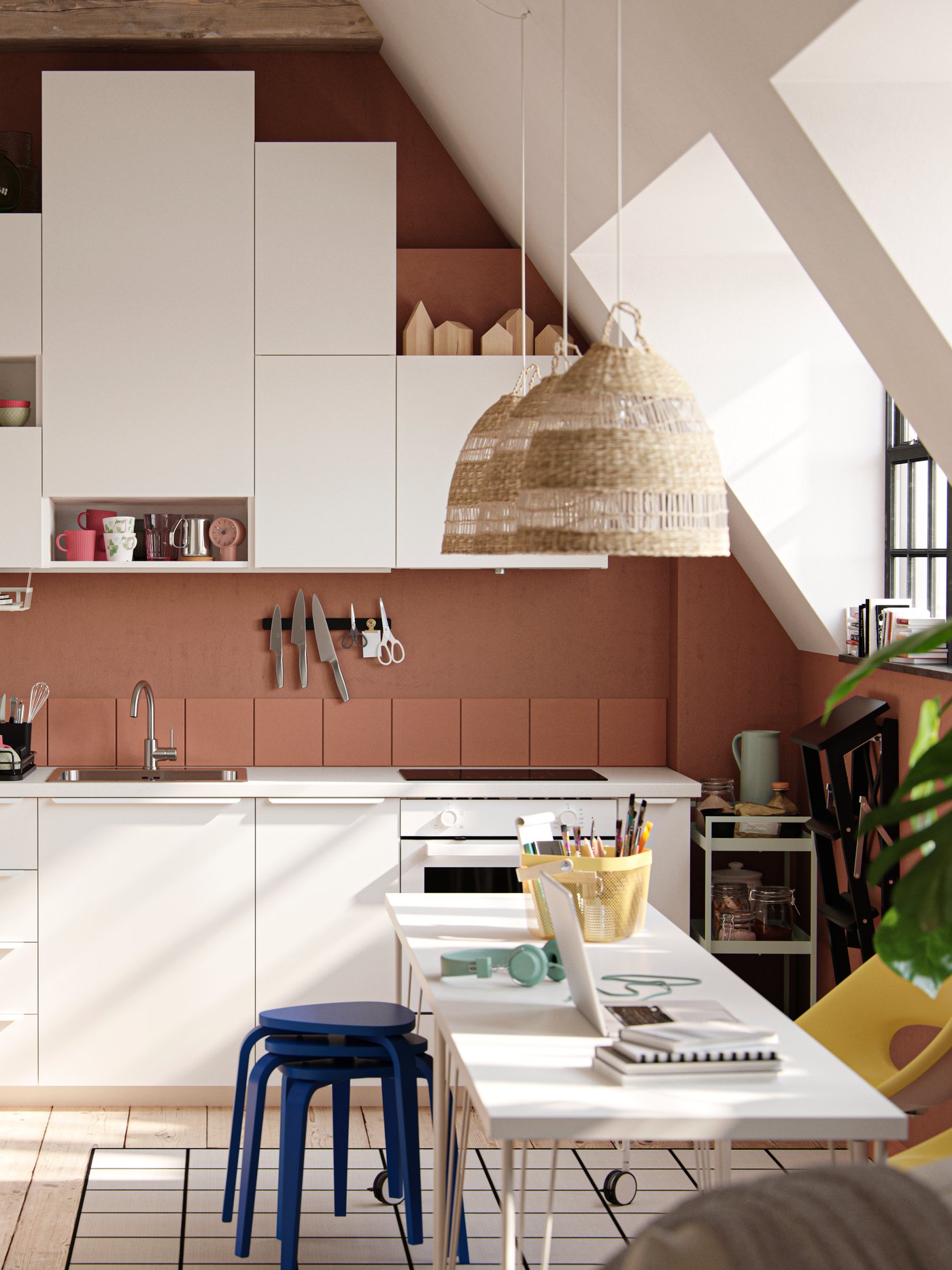 Ein Studio-Apartment mit großen Fenstern im Industriestil, dunklen terrakottafarbenen Wänden und einer Küche mit weißen VALLSTENA Küchenfronten.