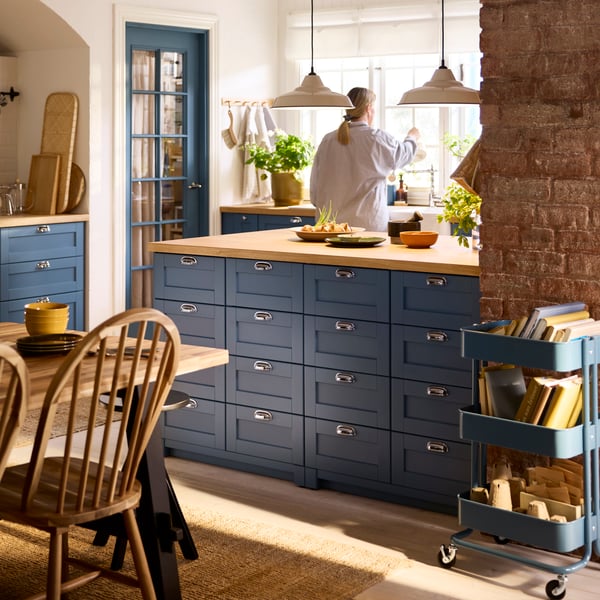 A kitchen island made of METOD cabinets has several drawers with LERHYTTAN blue fronts and chrome-plated ENERYDA handles.