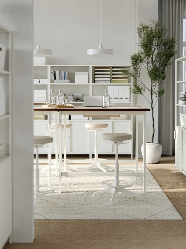 A casual meeting area with four high MITTZON conference tables and four LIDKULLEN sit/stand support. A beige cosy rug.