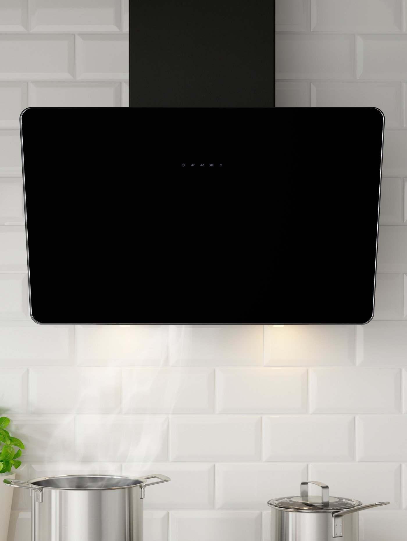 Zwarte FINSMAKARE wandgemonteerde afzuigkap aan een witte wand, boven twee roestvrijstalen pannen.