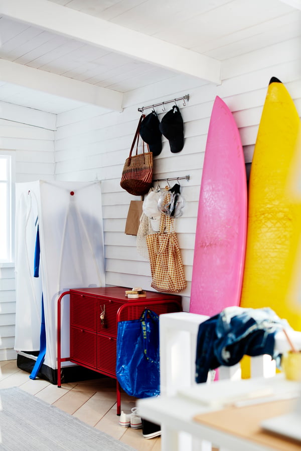 Ecke eines weiss vertäfelten Zimmers, u. a. mit einem VUKU Kleiderschrank. Daneben lehnen zwei Surfbretter an der Wand.
