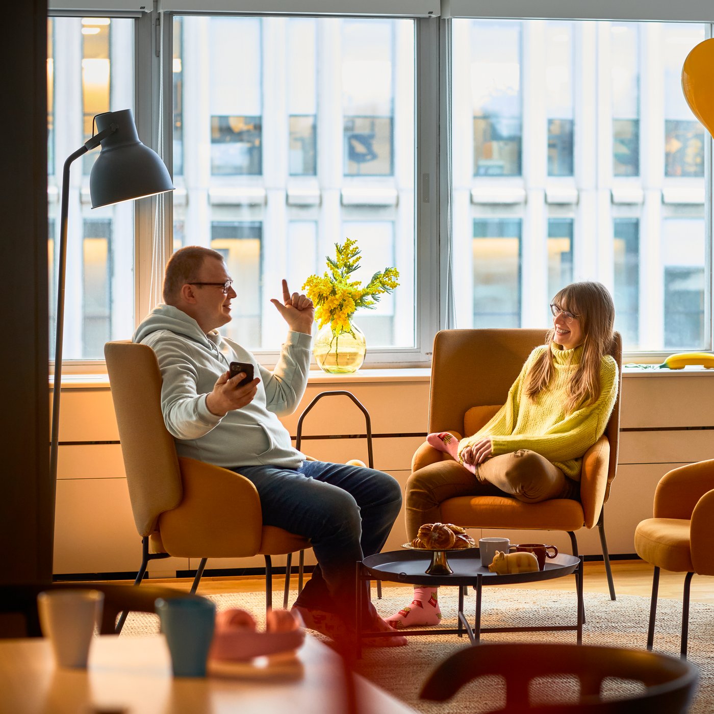 Två personer sitter i vars en orange fåtölj och pratar.