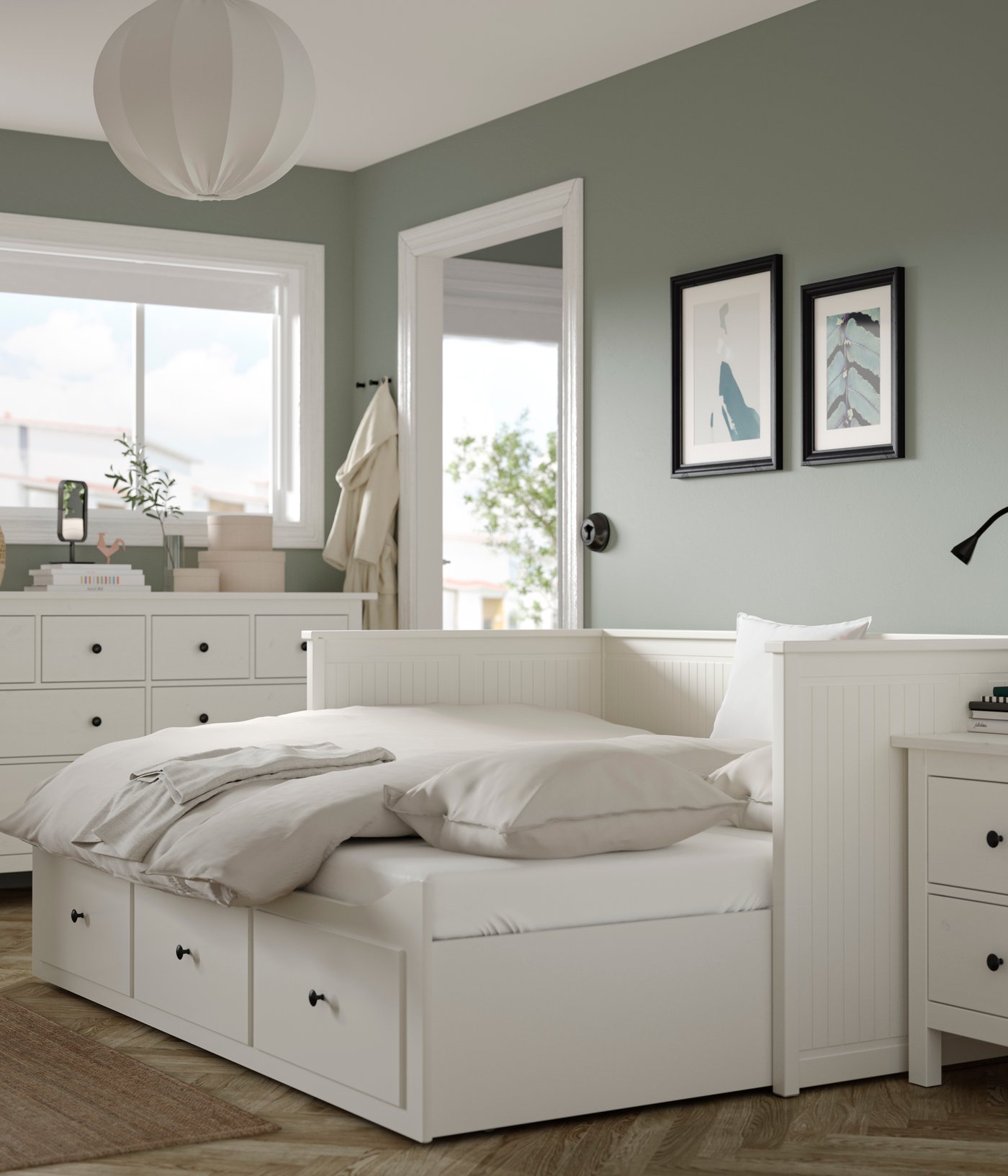 HEMNES-soffasäng i ett ljust rum med gröna väggar. Sängen har beige lakan.