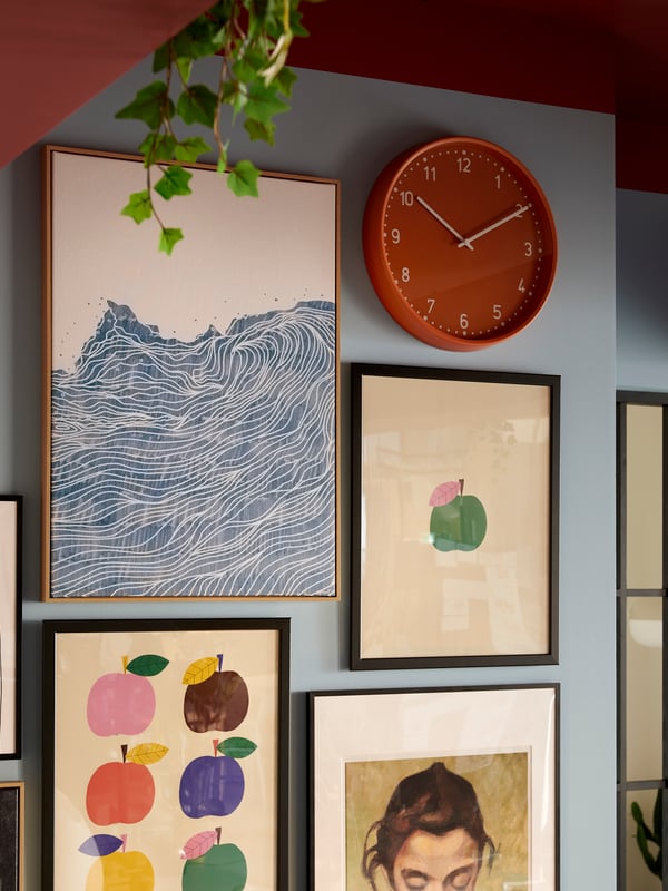 A brightly coloured room with a wall section filled with framed artwork and an orange BONDIS clock.
