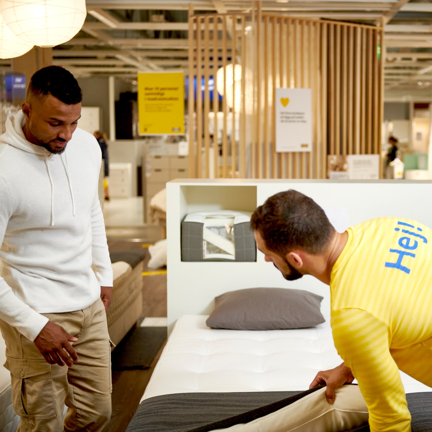 An IKEA co-worker advising two customers in the mattress studio
