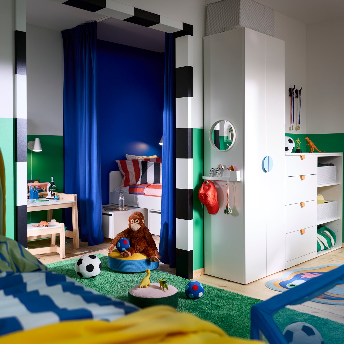 Armoire-penderie LASTARE avec tiroirs, rangement ouvert et crochets dans une chambre d’enfant avec des jouets, des livres et du matériel de sport.