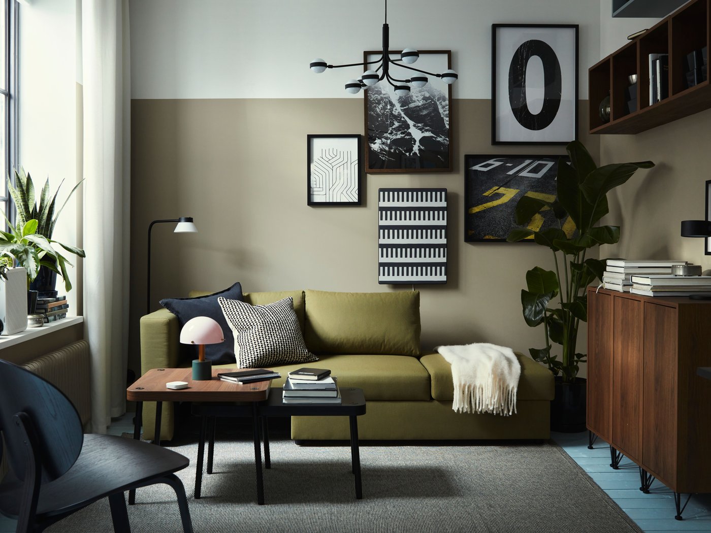 Een moderne woonkamer in aardetinten met een groene SKÖNABÄCK tweezits slaapbank en houten salontafels.