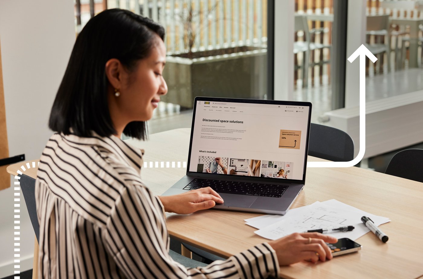 Woman with a laptop doing calculations using a calculator.