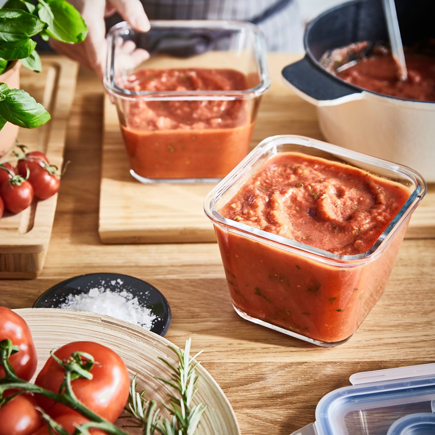 Träyta i kök med burkar tomatsås, färska tomater och örter – en rustik scen som antyder matlagning med italienska smaker.
