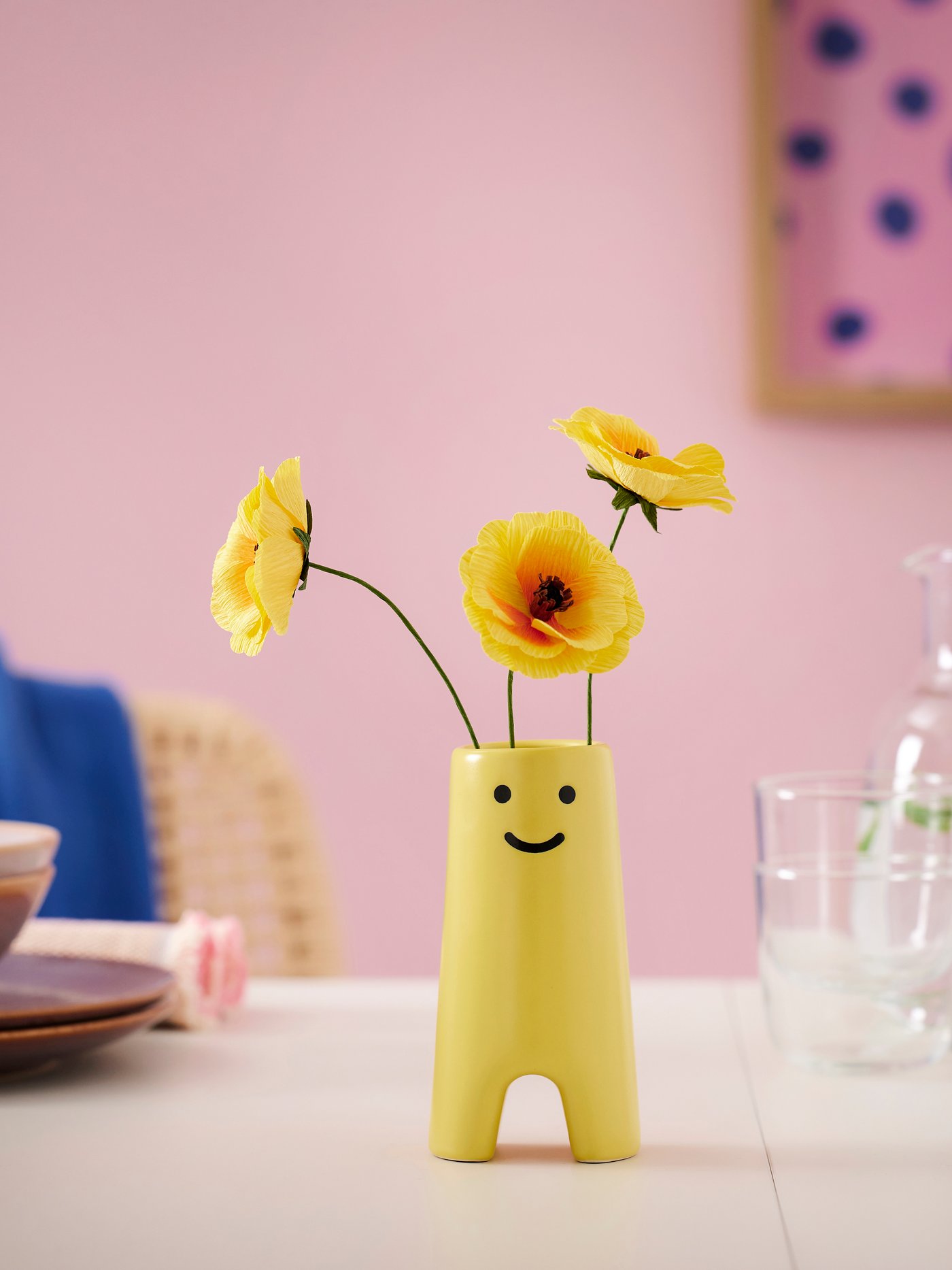 A yellow vase with yellow paper flowers.