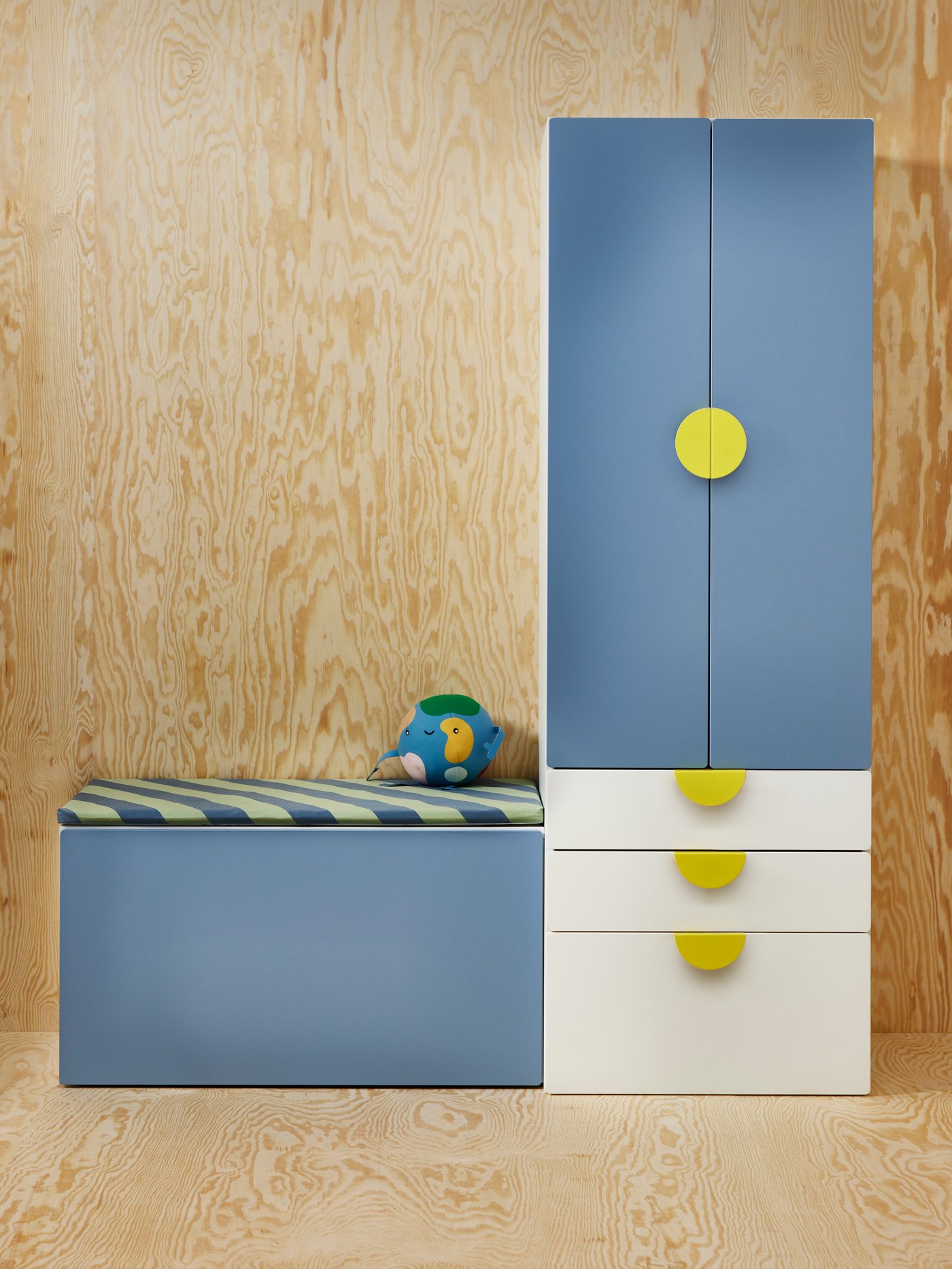 Dormitorio con una combinación de almacenaje SMÅSTAD azul con varios tiradores BEGRIPA amarillos y un cojín de banco BÄNKKAMRAT .