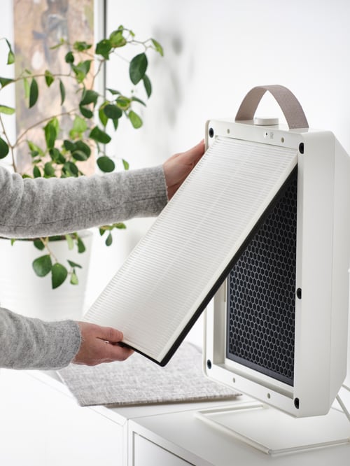 Prim-plan al femeii care deschide un purificator de aer alb cu filtru de particule și filtru de gaz care are o dimensiune mică și o greutate mică.