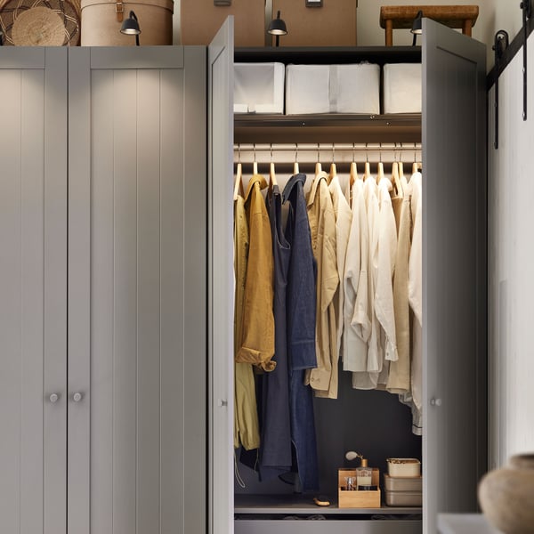 A dark grey/grey PAX/GULLABERG wardrobe combination with two doors open showing hanging clothes and storage boxes on shelves.