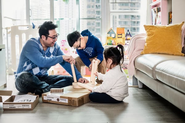 Une famille en train d’assembler un meuble IKEA dans leur salon.