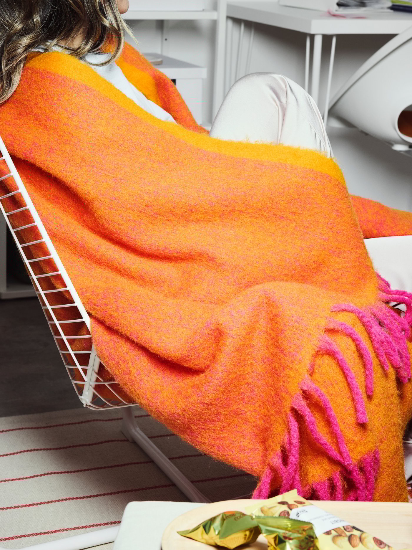 Een persoon is gewikkeld in een oranje/roze KLIPPOXEL plaid.