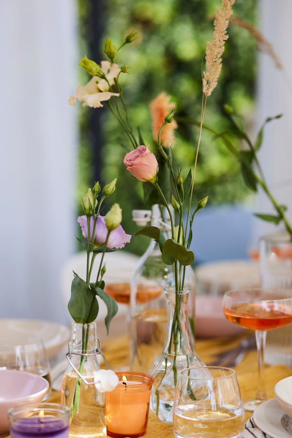 Primo piano di un vaso sottile con alcuni fiori ed erbe al suo interno