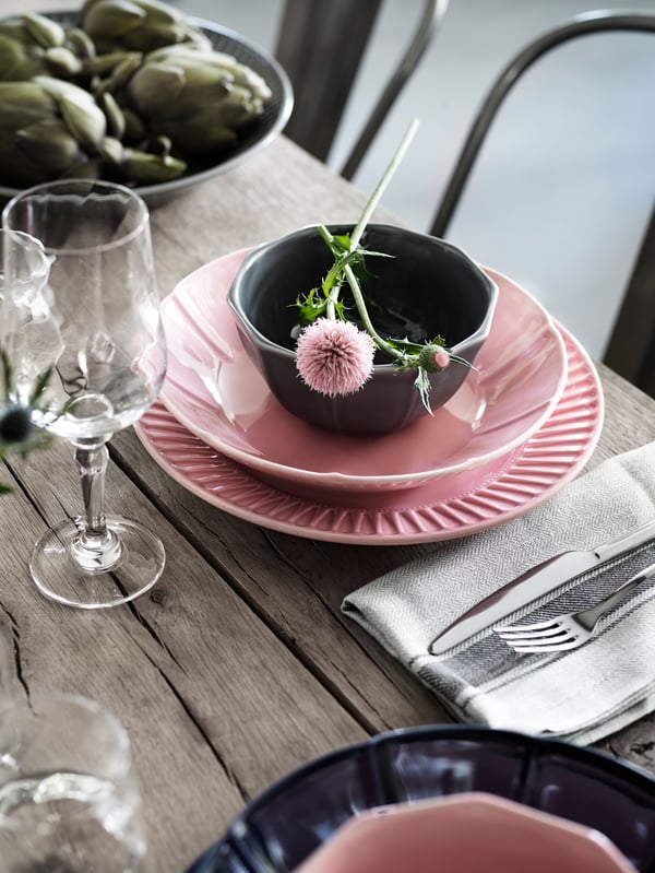 A table setting with STRIMMIG flower-inspired tableware in green. There is also a white plate with two eggs on the table.