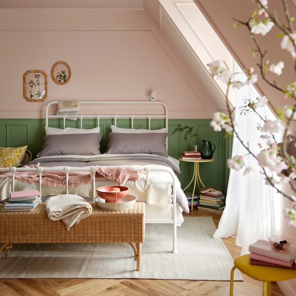 A stylish bedroom featuring a grey LUKTVICKER comforter set on a white STJÄRNÖ bed frame, accented with decorative items.