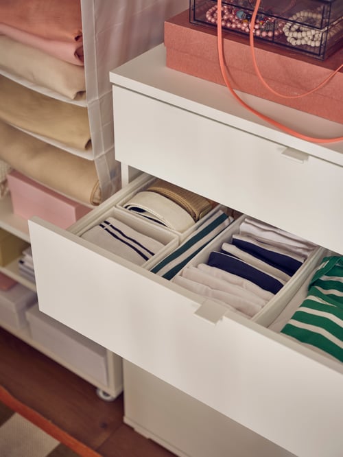 Dormitor cu un set dreptunghiular de 6 cutii SKUBB depozitate în interiorul unui dulap alb cu 4 sertare VIHALS