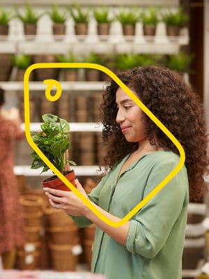 Kobieta trzymająca doniczkę z kwiatkiem w rękach w sklepie IKEA