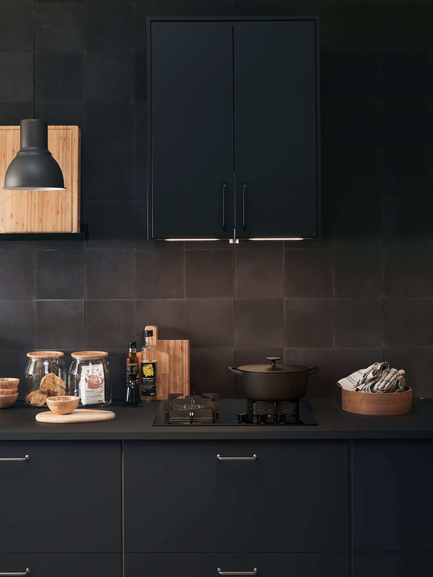 Sukalde-eremua altzairu herdoilgaitzezko erauzgailu grisa duen estalkidun lapiko beltz baten gainean jarrita.