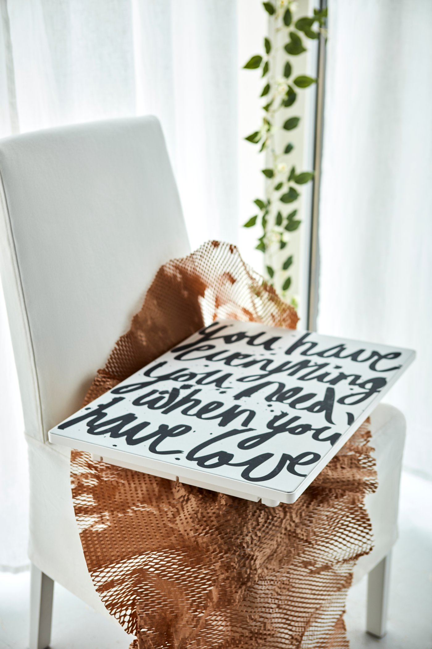 A SYMFONISK picture frame with a WiFi speaker with a graphic message of love lying on some netting on a textile chair.