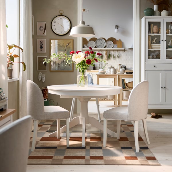 La salle à manger lumineuse est équipée d'une table extensible ROSENTORP blanche, de deux chaises ROSENTORP et d'une chaise haute ANTILOP avec plateau.