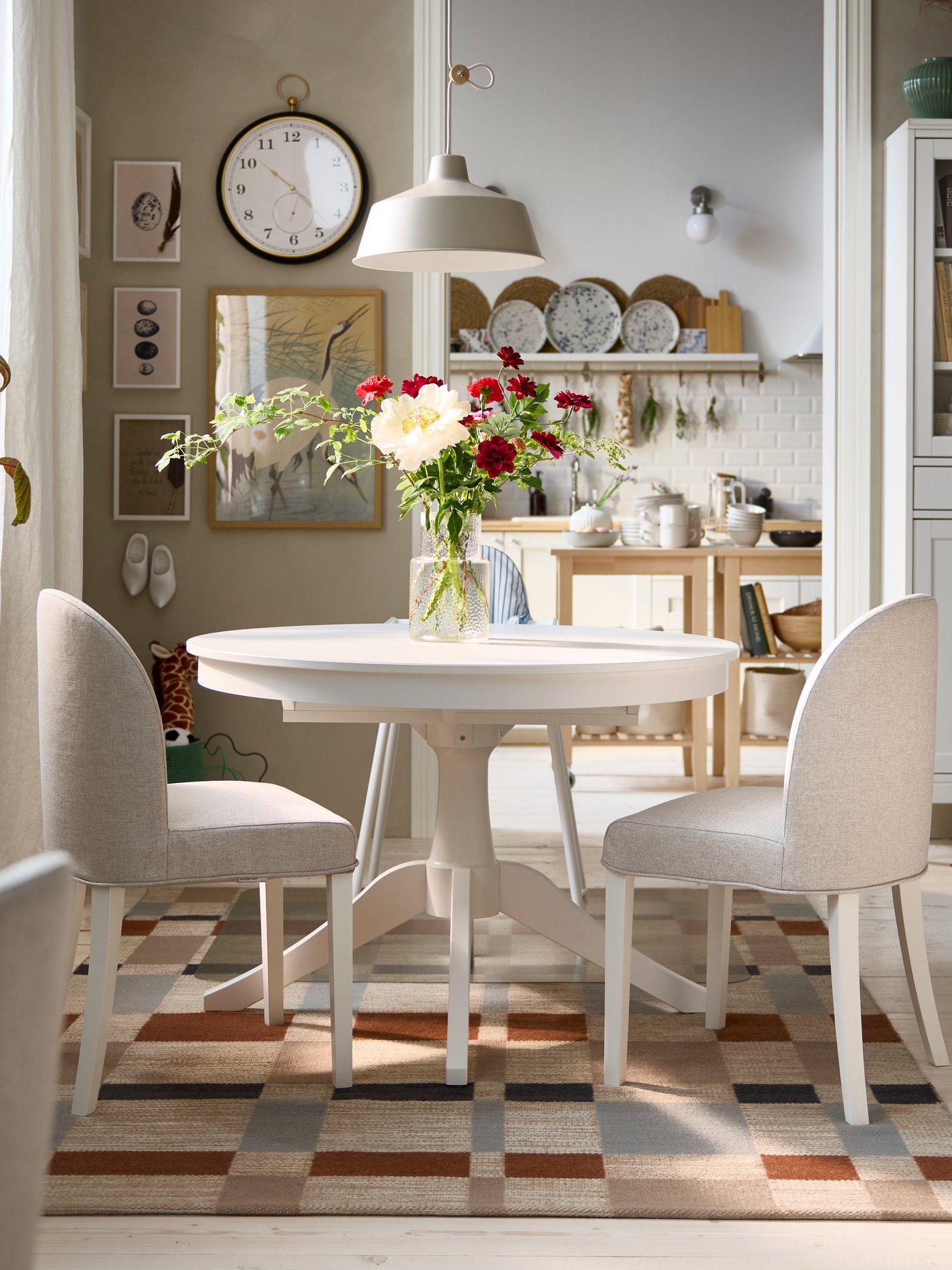 A bright dining area has a white ROSENTORP extendable table, two ROSENTORP chairs and an ANTILOP highchair with tray.