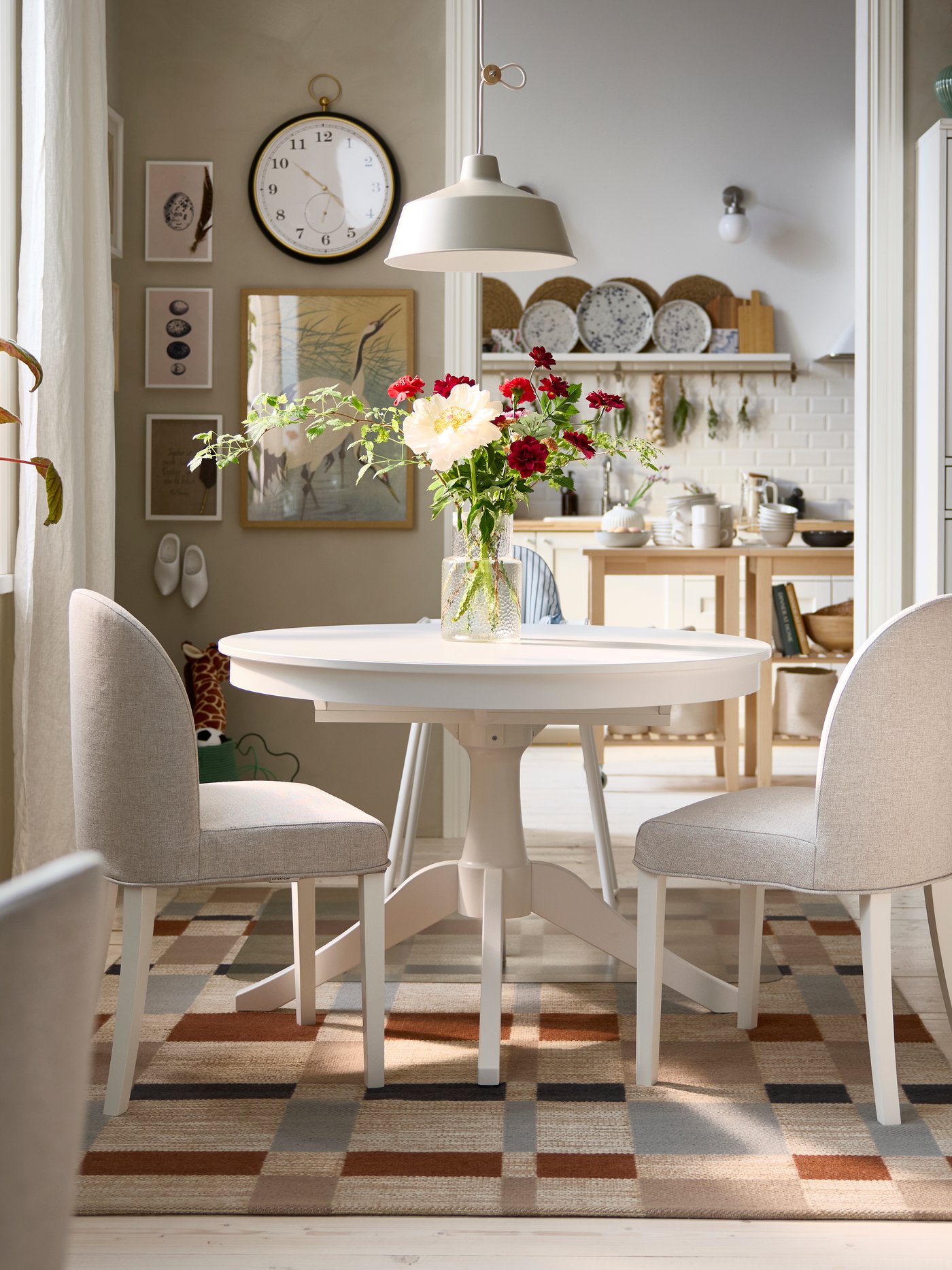 A bright dining area has a white ROSENTORP extendable table, two ROSENTORP chairs and an ANTILOP highchair with tray.