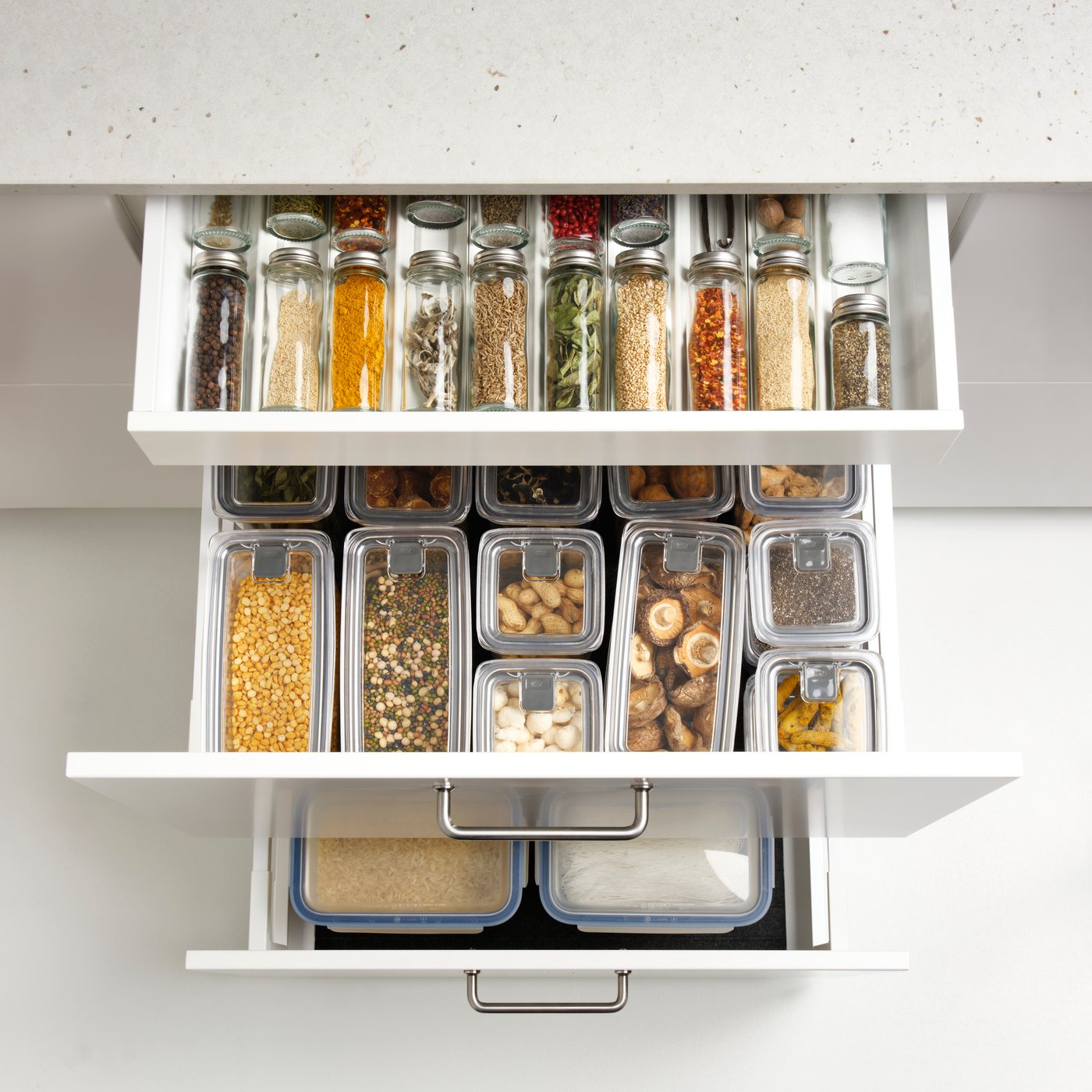 A kitchen drawer with  spice jars and containers shows clear glass CITRONHAJ spice jars made from glass and stainless steel.