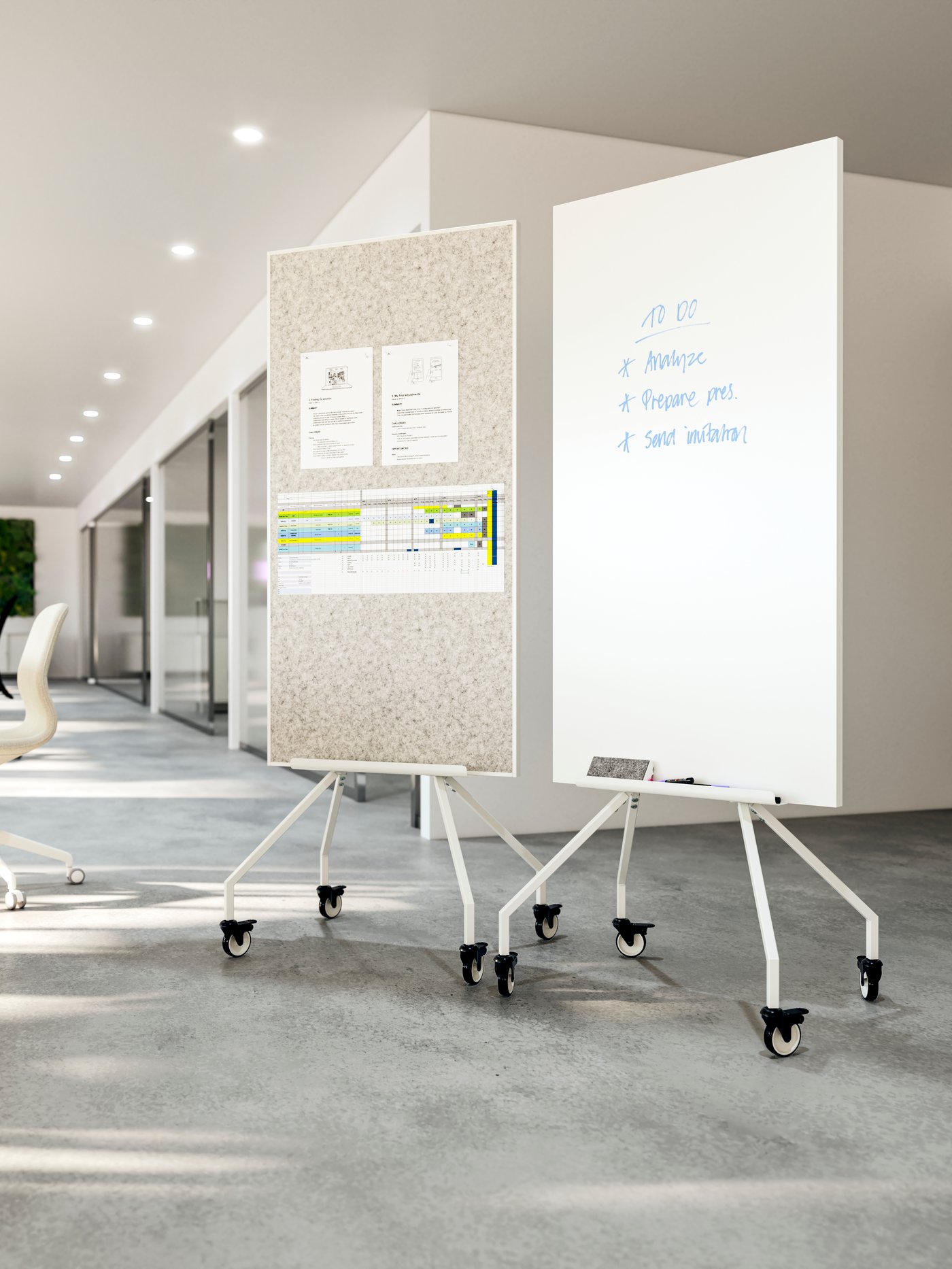 Un pasillo de una oficina con dos tableros ELLOVEN con ruedas, uno es de corcho y tiene papeles pegados, el otro es una pizarra blanca con cosas escritas con plumón.