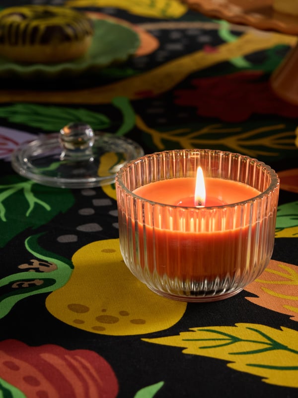 Et HÖSTAGILLE duftlys med sandaltræ og patchouli i glas i stuen