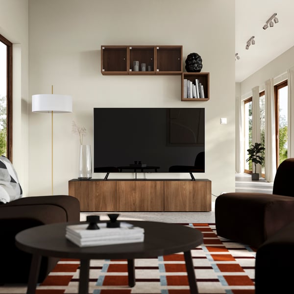 A brown BESTÅ TV unit with walnut‑effect doors and a brown EKET cabinet in walnut effect mounted above the TV in the living room.