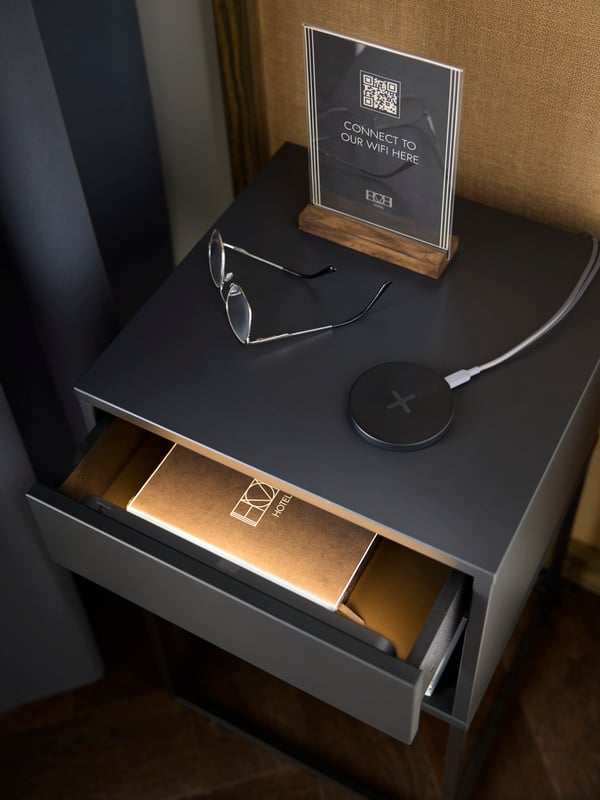 A slightly opened hotel bedside drawer is softly lit by a super slim, battery-operated KÖLVATTEN LED lighting with sensor.