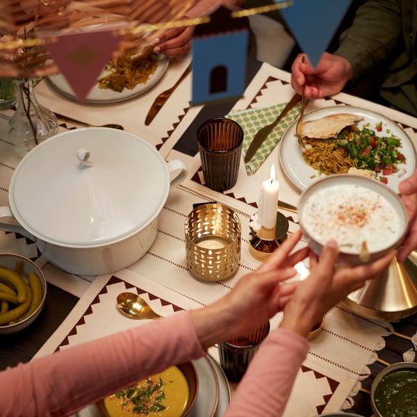 A white GOKVÄLLÅ soup tureen is placed on a dining table surrounded by people enjoying a meal.
