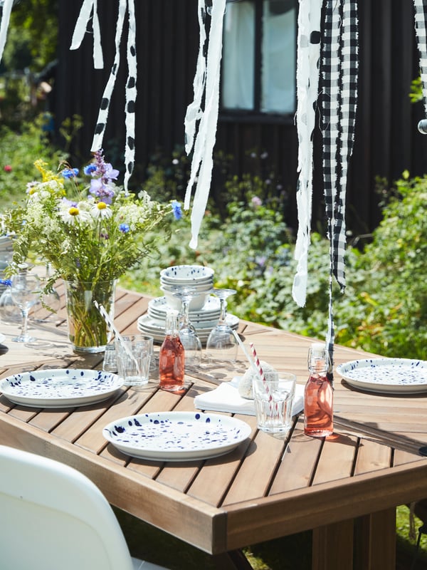 NORRMANSÖ wood table in the garden is set and decorated for a Midsummer celebration.