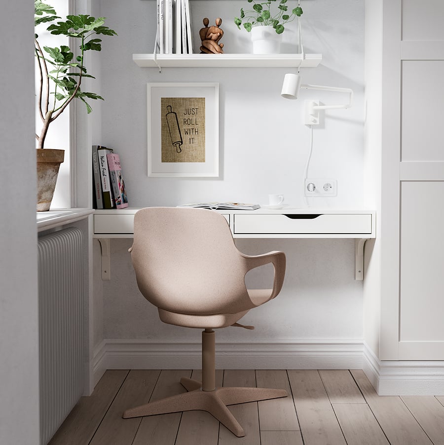 Una silla giratoria ODGER beige frente a un estante EKBY ALEX empotrado al muro como escritorio en un rincón, bajo dos repisas BERGSHULT blancas. 