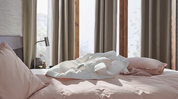In a bedroom, a white duvet is placed on a bed with pink duvet covers.