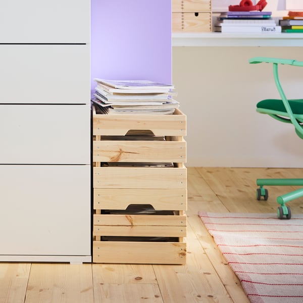 A room with a white VIHALS chest of 4 drawers, featuring a purple wall and wooden floor, beside natural wooden boxes.