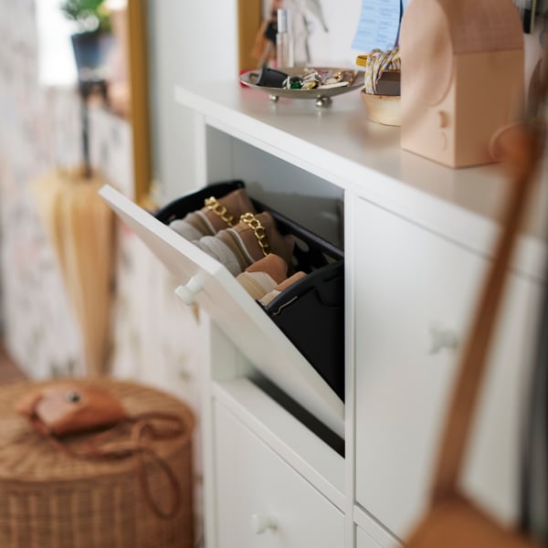 Un zapatero blanco GULLABERG con el compartimento superior abierto, mostrando dos pares de zapatos. Encima hay unas llaves y un altavoz.