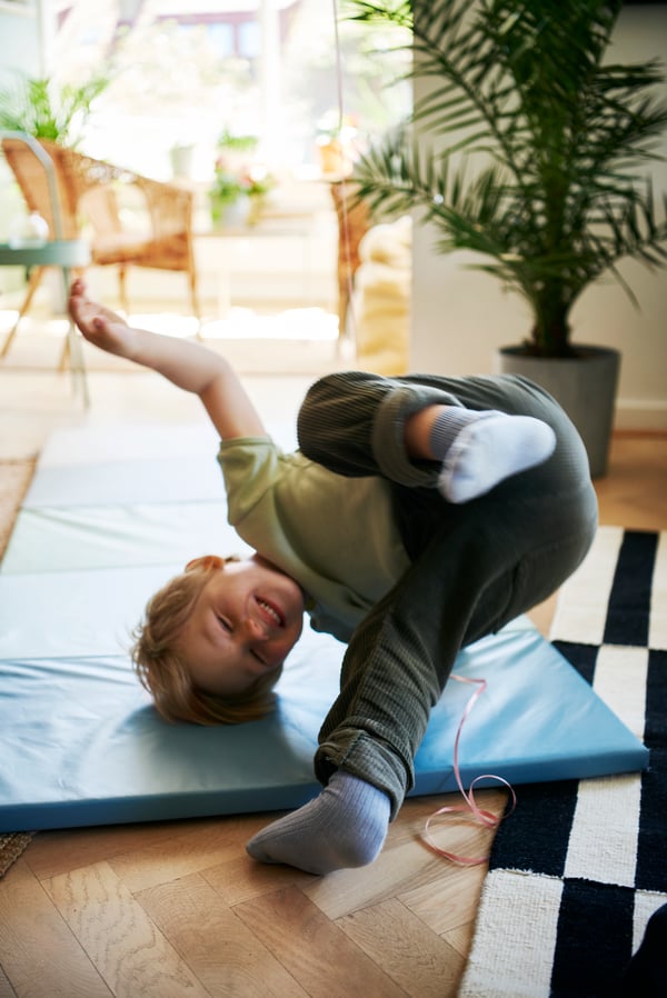 Young boy tumbling on a playmat.
