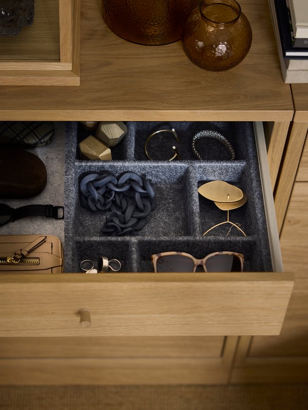 Lunettes de soleil et bijoux dans un organiseur RAGGISAR gris foncé placé dans le tiroir du haut d’une commode 6 tiroirs TONSTAD.