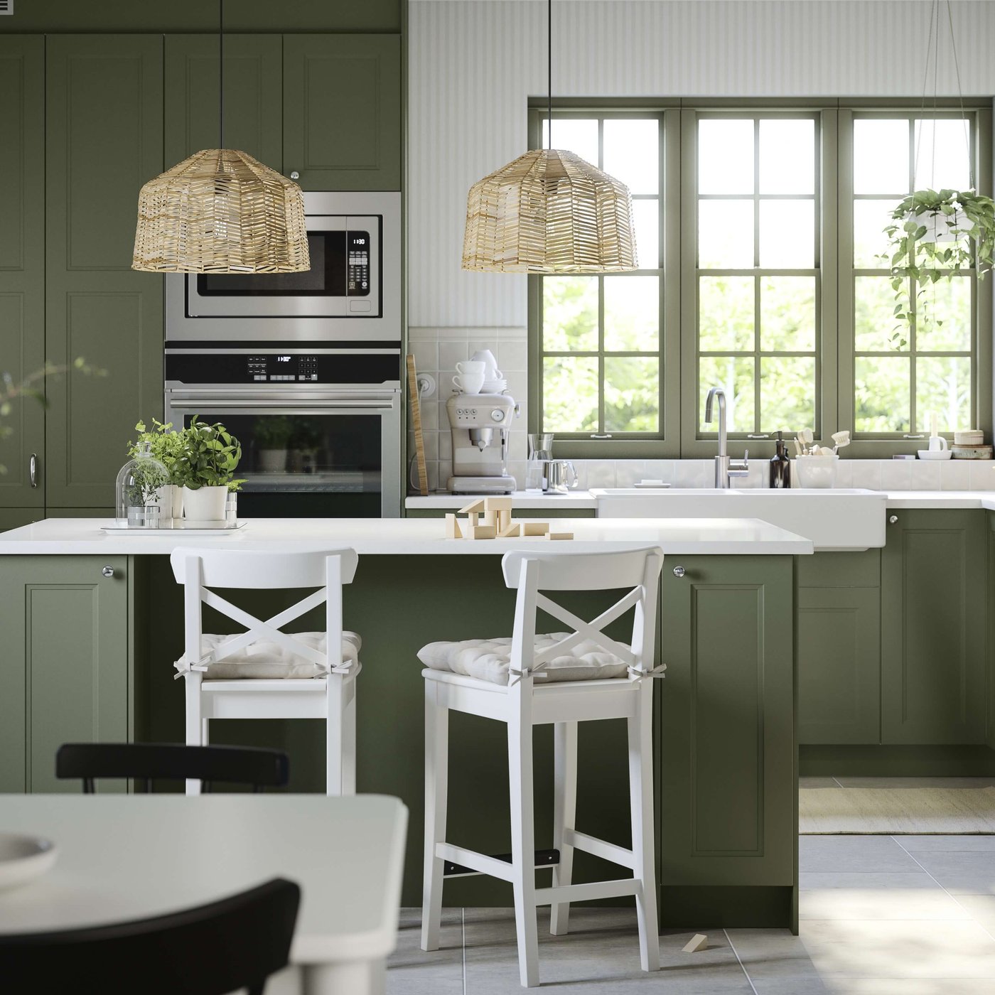 Green kitchen with a large island and bar stools.