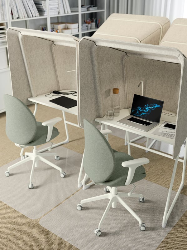Four cocoon-like shaped MITTZON focus workstations grouped together in a small office and two green chairs on castors.